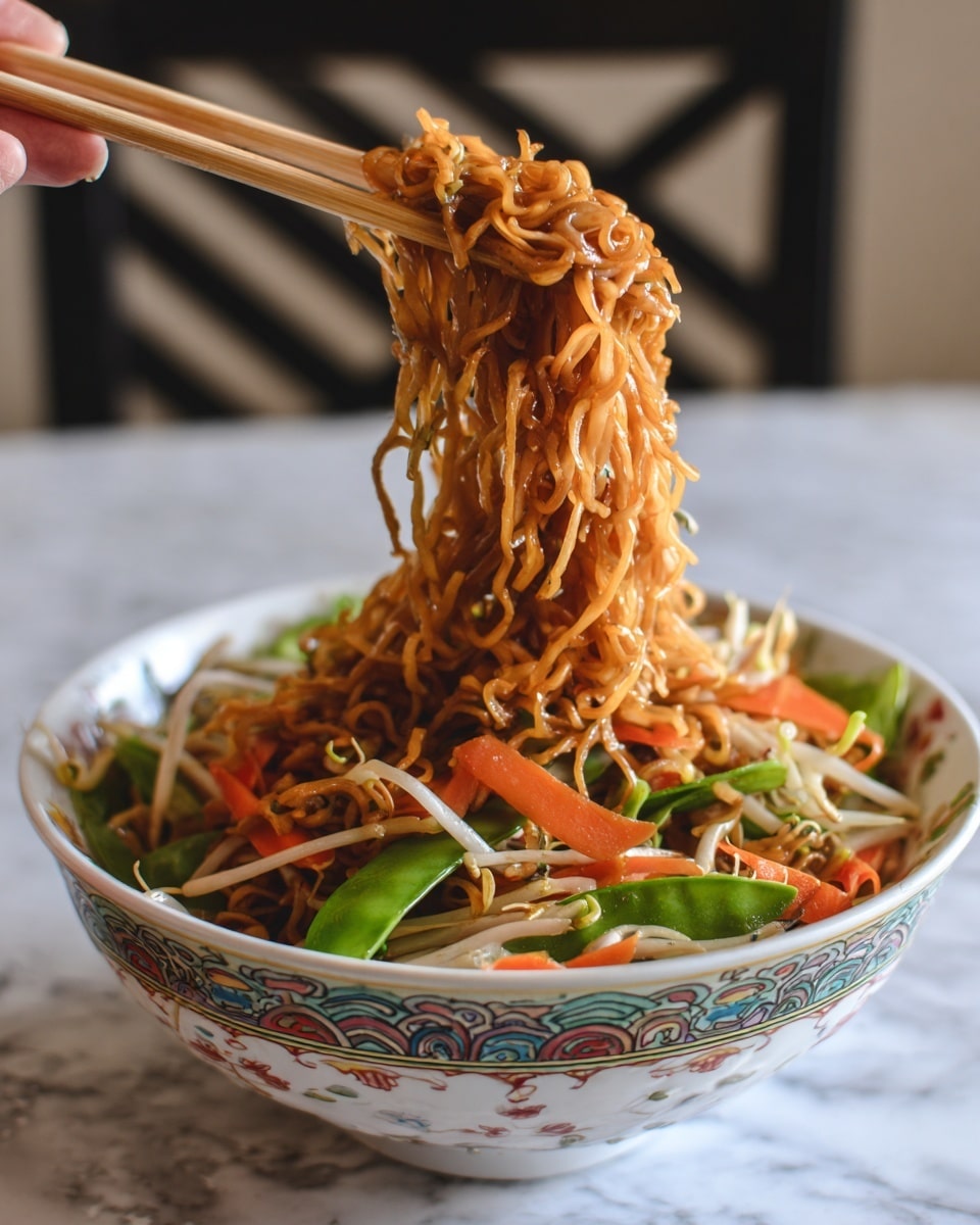 A close-up image shows thin cooked noodles lifted with a pair of light brown wooden chopsticks held by a woman's hand above a white bowl decorated with an orange, purple, and green floral and geometric pattern. The noodles have a shiny, glossy brown sauce coating, with bits of thin orange carrot strips and green vegetables mixed in. The bowl is full, with more noodles and vegetables visible inside. The background surface is a white marbled texture. photo taken with an iphone --ar 4:5 --v 7