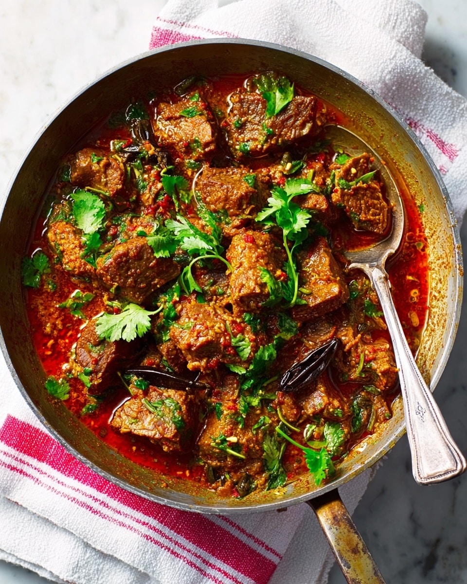 The image shows a pan filled with a rich meat stew. The stew has many pieces of browned meat coated in a thick reddish-brown sauce with visible spices and herbs. Bright green fresh cilantro leaves are scattered on top, adding bursts of color. There are also some whole spices like black cardamom pods nestled within the stew. The pan rests on a white marbled surface, with a white cloth featuring red stripes underneath it. A silver spoon is placed in the pan, partially immersed in the stew, ready for serving. photo taken with an iphone --ar 4:5 --v 7