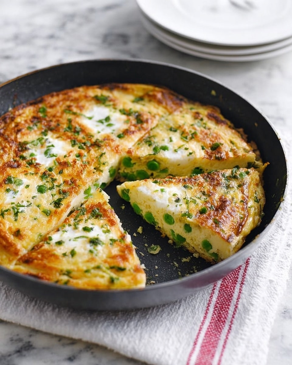 The image shows a round black pan with a golden brown frittata inside, cut into slices. The frittata has three white egg whites visible on top, with green pea pieces scattered throughout the middle layer. The texture appears fluffy and slightly crispy on the edges, with green herbs sprinkled over the top. The pan sits on a white marbled surface with a folded white cloth with red stripes underneath. There are a few white plates stacked in the background. Photo taken with an iphone --ar 4:5 --v 7
