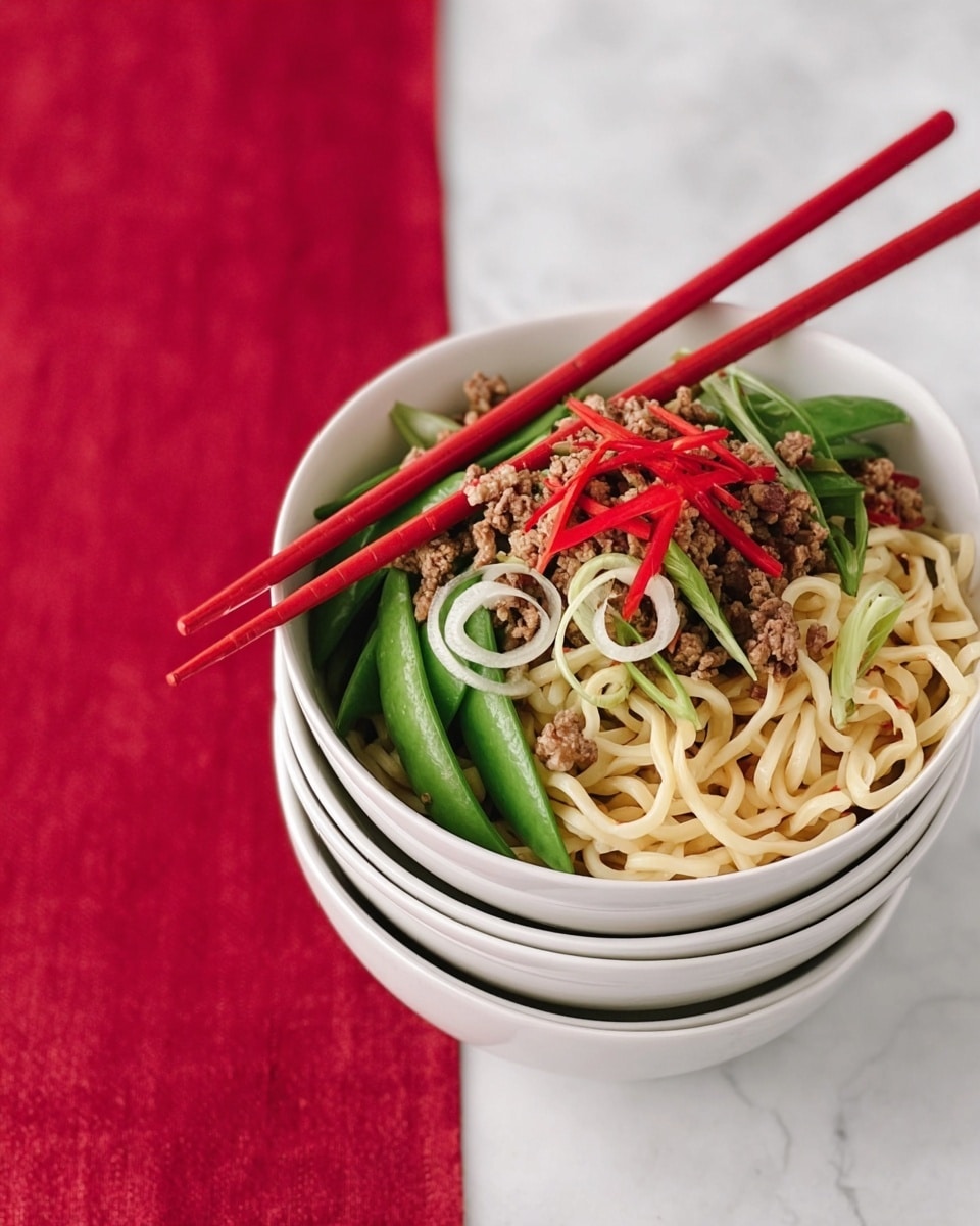 A stack of four white bowls with a ridged texture is shown on a white marbled surface covered by a red cloth. The top bowl is filled with three layers: the bottom layer consists of thick udon noodles that are pale cream and smooth. Above the noodles is a layer of ground meat that is brown and crumbly, mixed with bright green snap peas that add a fresh look. The top layer has thin strips of red chili pepper and white curled onion slices, adding color and texture. Two red chopsticks are placed in the bowl, held by a woman’s hand reaching from the top right corner. Photo taken with an iphone --ar 4:5 --v 7