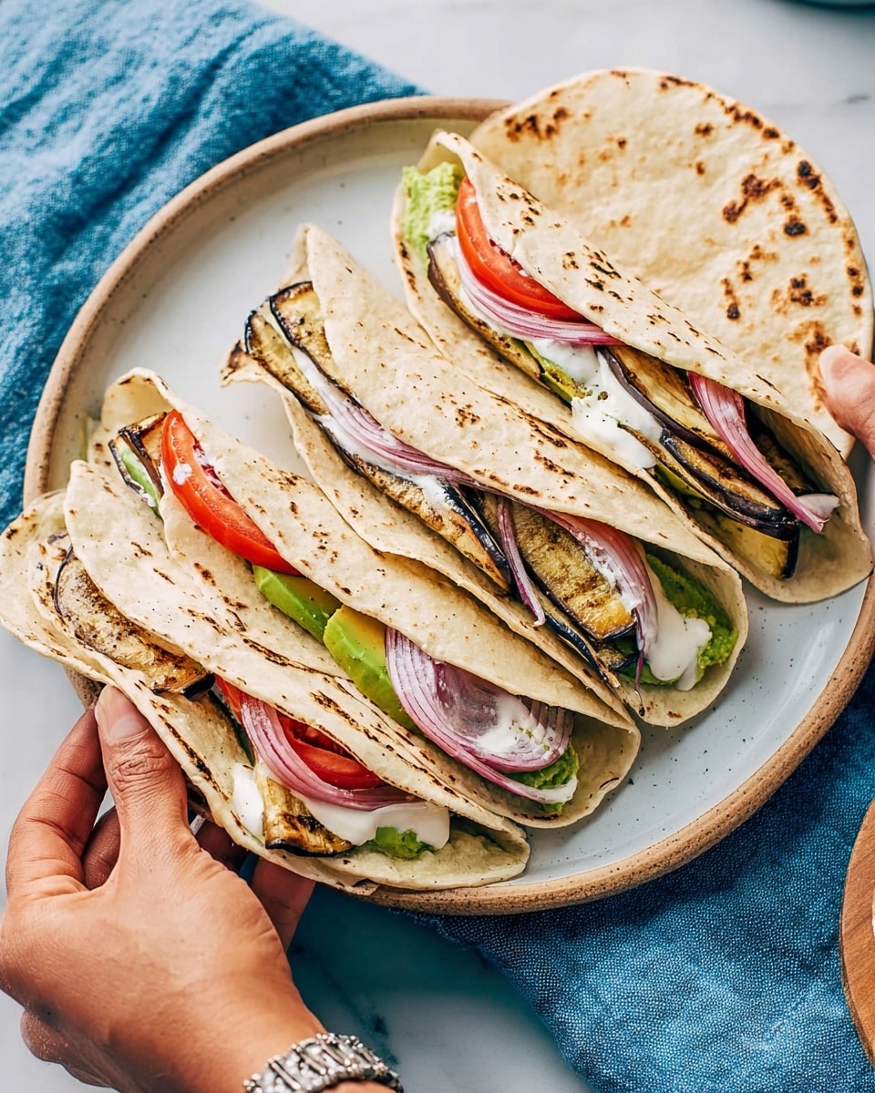 Four wraps are placed on a white plate, each wrap made of a light brown toasted flatbread folded in half. Inside the wraps, there are layers of green avocado slices, grilled dark brown eggplant pieces, bright red tomato slices, and thin strands of pickled pink onion. A drizzle of white sauce adds contrast on top of the vegetables. A woman's hand with a silver bracelet is holding the rightmost wrap from the side. The plate sits on a white marbled surface with a blue cloth partially visible behind it. photo taken with an iphone --ar 4:5 --v 7