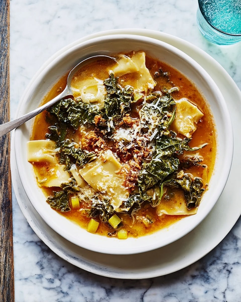 A white bowl filled with a warm soup that has three main layers: at the bottom, wide, flat beige pasta sheets partially submerged in light brown broth; the middle layer consists of dark green leafy kale, and small cube-shaped pieces of orange vegetables scattered throughout; on top, there are bits of browned meat or sausage with some grated cheese sprinkled around, adding texture and a light contrast. A silver spoon rests on the left edge of the bowl. The bowl sits on a white plate placed on a white marbled surface. A glass of clear liquid with ice is partially visible in the upper right corner. Photo taken with an iphone --ar 4:5 --v 7