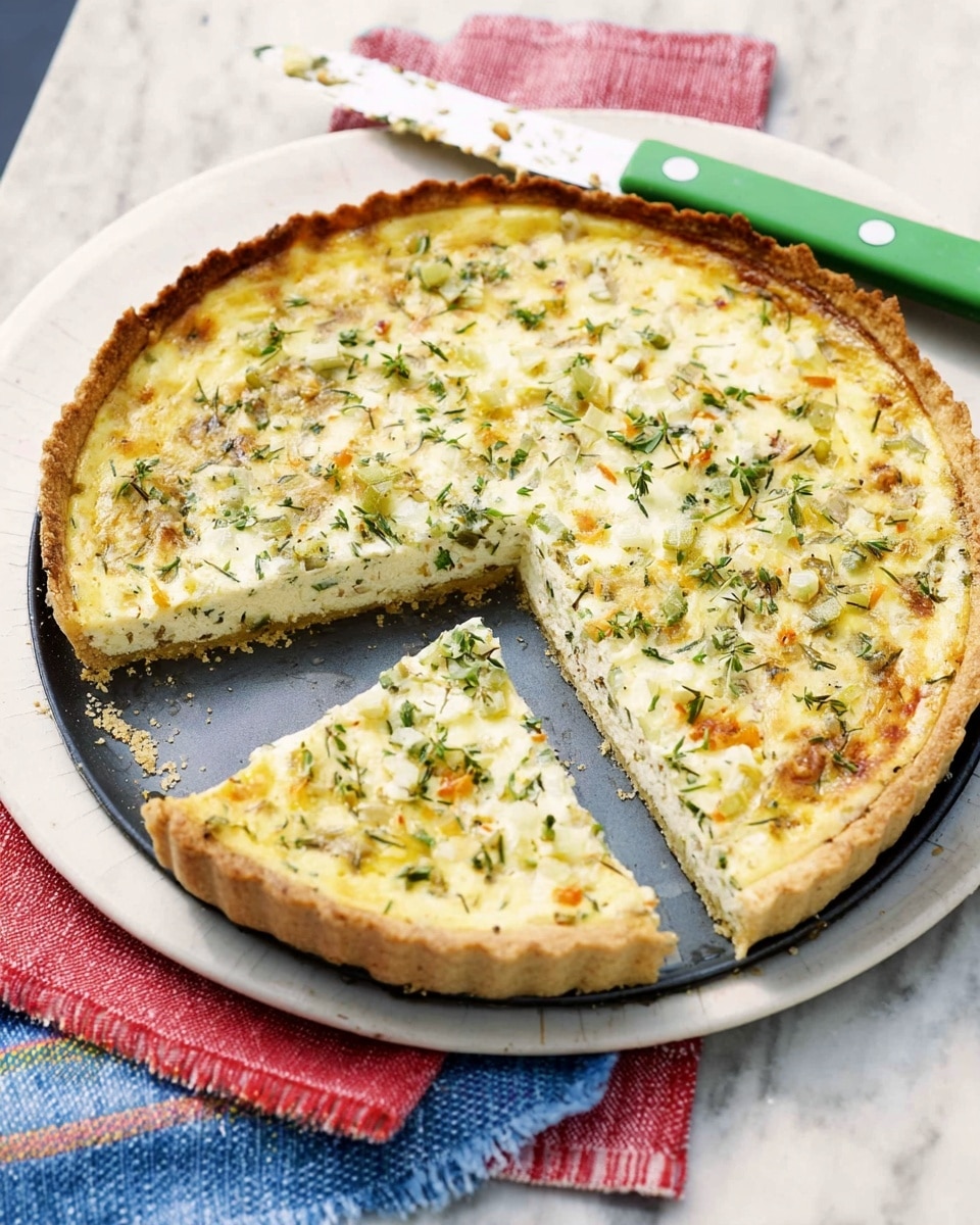 A round savory pie is shown in a dark baking tin, sitting on a white marbled surface with a folded cloth beneath it that has red, blue, yellow, and white stripes. The pie has a golden-brown thin crust around the edges, a creamy white filling mixed with chopped light green herbs and small chunks of white cheese, giving a textured, slightly uneven surface. One slice has been removed, revealing the crust’s thickness and creamy filling inside. A knife with a white blade and green handle rests on the right side of the baking tin. Photo taken with an iphone --ar 4:5 --v 7