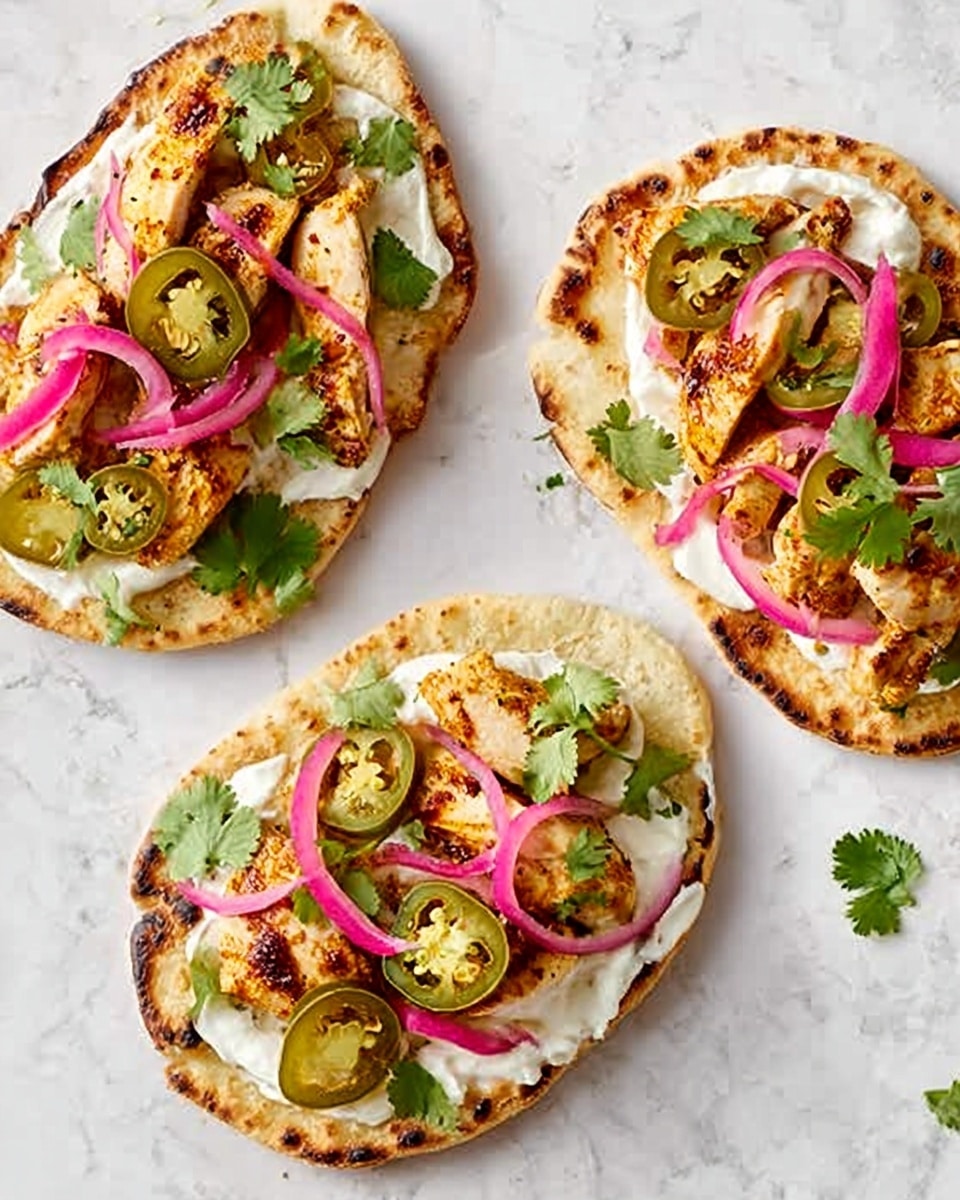 Three small flatbreads are laid out on a white marbled surface. Each flatbread has a base layer of white sauce spread evenly, topped with golden-brown grilled chicken pieces placed in the center. On top of the chicken, there are thin slices of green jalapeño, bright pickled pink onions, and a few fresh green cilantro leaves scattered around. The flatbreads have a slightly charred, crispy edge with a light brown color. Photo taken with an iphone --ar 4:5 --v 7