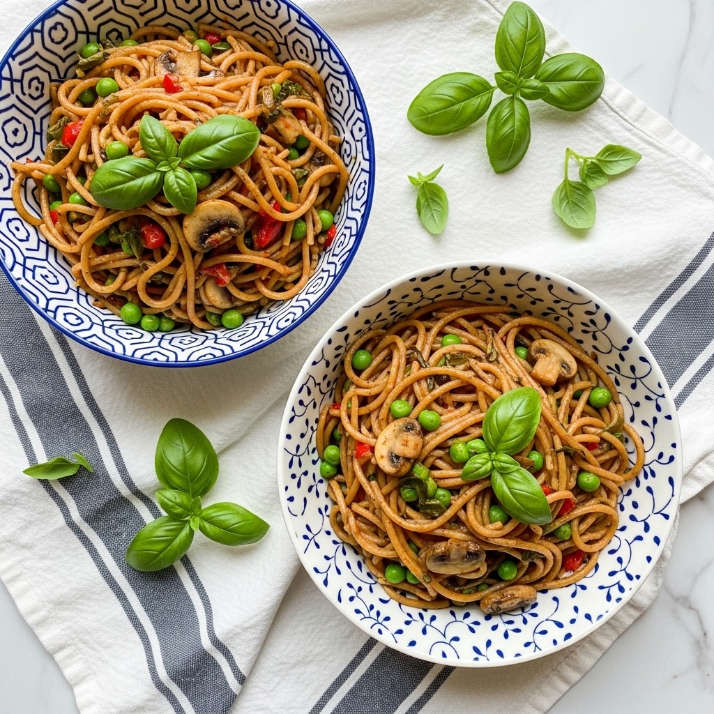 Two white bowls with blue patterns hold twisted brown spaghetti mixed with green peas and small mushroom pieces. Each bowl has a bright green basil leaf on top, and tiny red bits are scattered among the pasta. The bowls rest on a white marbled surface covered with a white and gray striped cloth, with fresh green herb stems lying nearby. The pasta looks soft and lightly sauced, with the peas and mushrooms giving spots of green and beige color within the noodles. Photo taken with an iphone --ar 4:5 --v 7