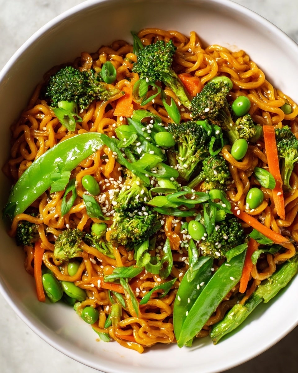 A white bowl filled with curly, saucy noodles that have a rich orange-brown color, topped with bright green snap peas, small broccoli florets, and thin strips of orange carrot. Scattered green onion slices and small white sesame seeds are sprinkled over the dish, adding texture and contrast. The bowl sits on a white marbled surface, with the ingredients looking fresh and vibrant. photo taken with an iphone --ar 4:5 --v 7