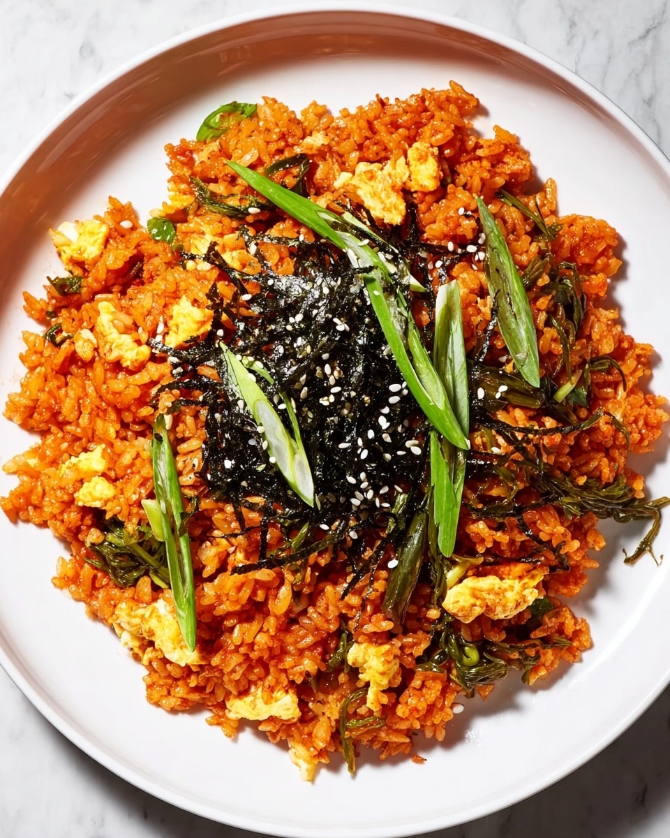 A plate of bright orange fried rice is presented on a white dish, with visible layers of cooked rice mixed evenly with small pieces of scrambled yellow eggs and green vegetables. Dark thin strips of seaweed are scattered on top, adding texture and contrast, while white sesame seeds sprinkle over the seaweed. Fresh light green slices of scallions are placed on top for a fresh pop of color. The rice has a slightly glossy look, indicating it is well-cooked and flavorful, all set against a white marbled surface. photo taken with an iphone --ar 4:5 --v 7