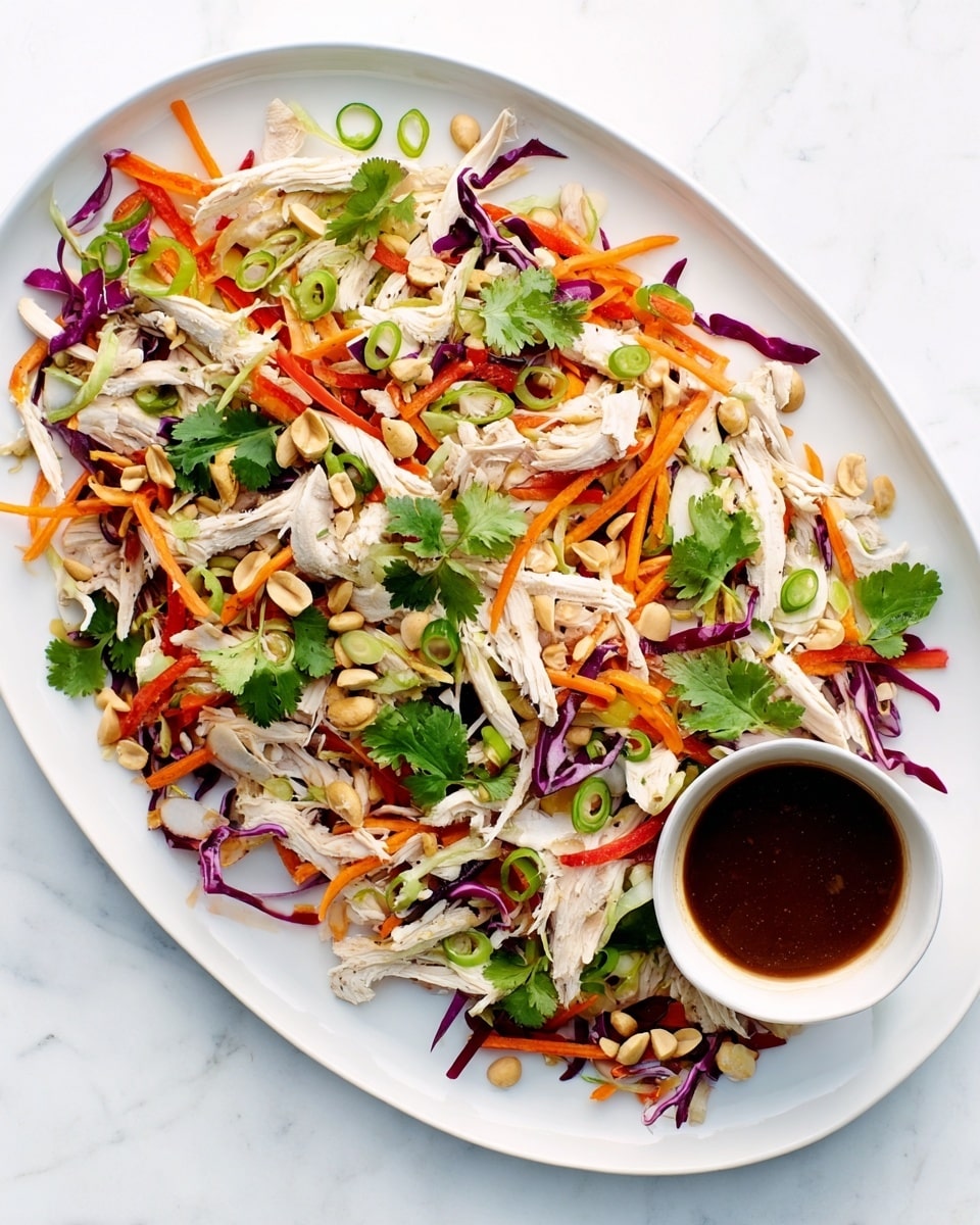 The dish is served on a white rectangular plate with a white marbled surface underneath. It has shredded white chicken pieces spread across the plate mixed with thin, long strips of bright orange carrots and purple cabbage. There are also sliced light green scallions and whole green cilantro leaves scattered evenly on top. Small chopped peanuts are sprinkled over everything. On one side of the plate is a small white round bowl filled with a dark brown sauce. The textures vary from soft chicken to crunchy vegetables and nuts, giving a colorful and fresh look. Photo taken with an iphone --ar 4:5 --v 7