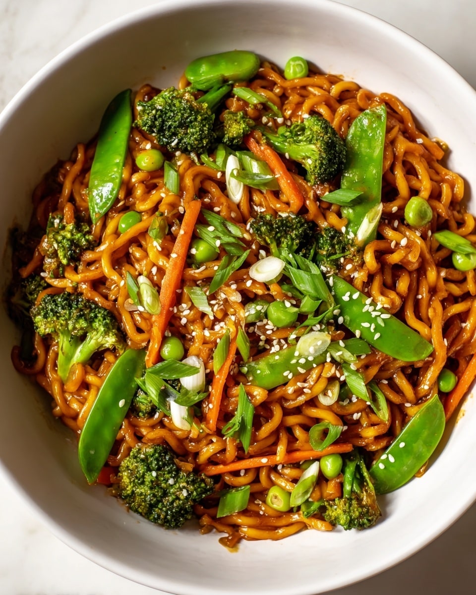 A white bowl filled with curly, orange-brown noodles at the bottom, cooked with sauce giving them a shiny texture. On top, bright green pieces of broccoli and whole snap peas are scattered, along with thin, bright orange carrot sticks. Fresh chopped green onions are sprinkled over everything, along with small white sesame seeds adding extra detail. The bowl sits on a white marbled surface. photo taken with an iphone --ar 4:5 --v 7