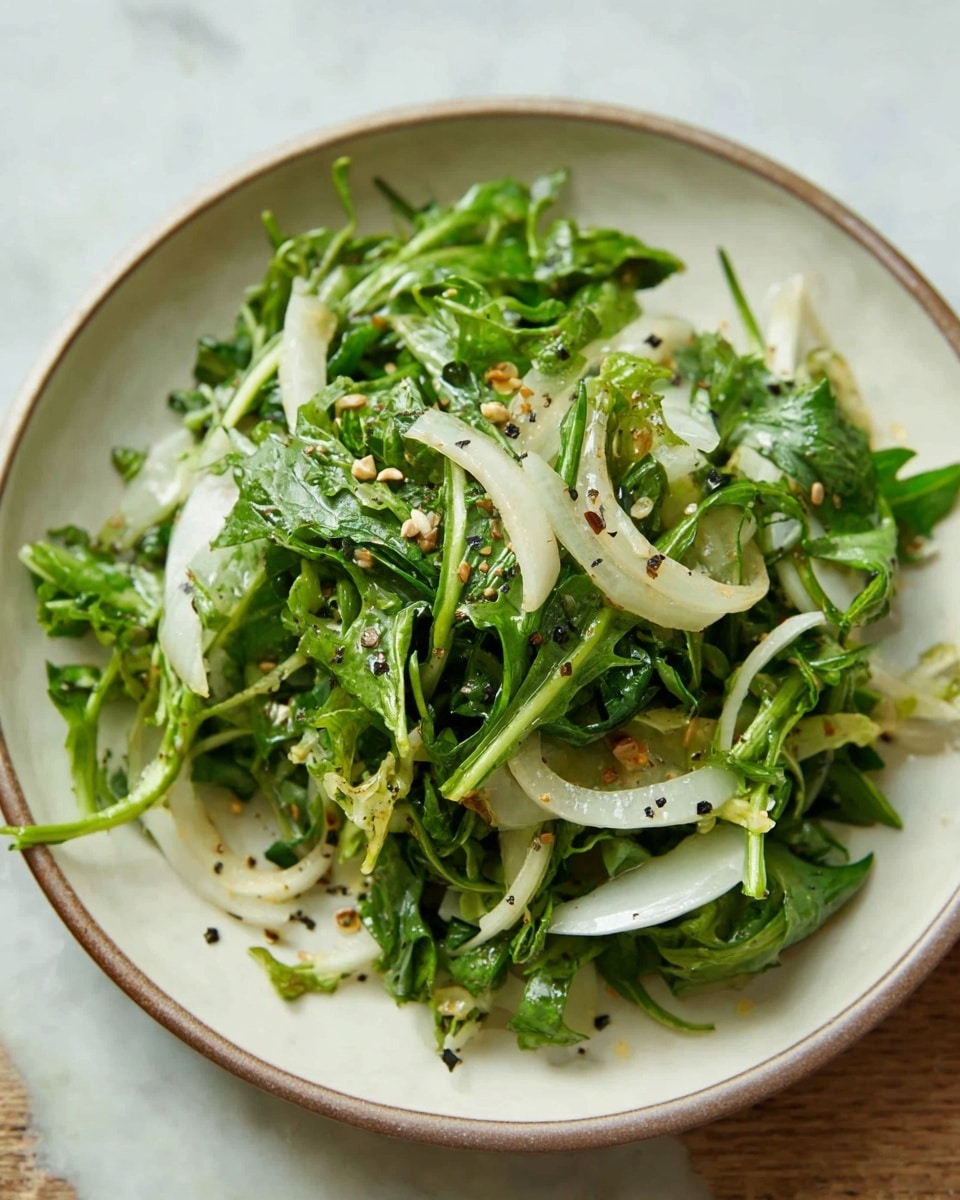 A simple salad is shown in a shallow white bowl, filled with a mix of green leafy vegetables that have jagged edges and slender stems, giving the salad a fresh and natural look. Interspersed within the green leaves are thin, white, slightly curved vegetable slices that add contrast. Small light brown seeds are sprinkled lightly over the top, adding texture and color variation. The salad looks lightly dressed, with tiny black pepper flakes sprinkled over it. The bowl sits on a surface with white marbled texture, enhancing the fresh and clean feeling of the dish. photo taken with an iphone --ar 4:5 --v 7