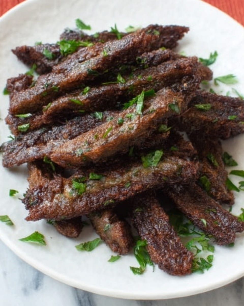 The image shows a white plate piled with several pieces of dark brown, crispy fried food that looks like strips of meat. The meat pieces have a textured, crunchy surface with some small green herb pieces scattered on top, adding a fresh touch of color. The background consists of a white marbled surface, and part of a woman's hand is visible near the plate, suggesting it is about to pick up one of the strips. Photo taken with an iphone --ar 4:5 --v 7