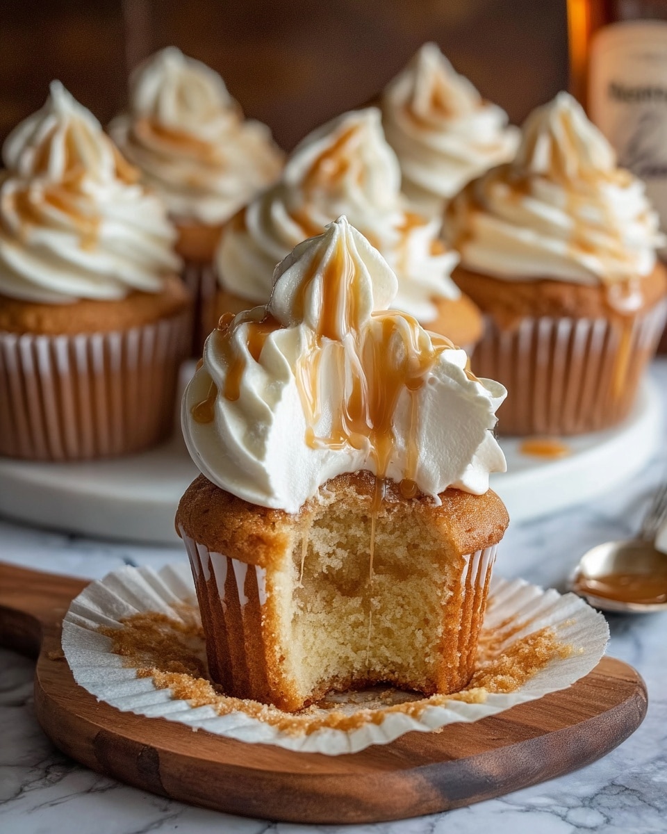 The image shows a close-up of a cupcake with four main layers. The bottom layer is the cupcake itself, which is golden brown and spongy in texture, partially wrapped with an off-white paper liner that is peeled back and sits on a wooden board. Above this is a thick middle layer of creamy white frosting inside the cupcake, visible because a bite is taken out of it. The top layer is a swirl of smooth, white whipped frosting with light brown streaks drizzled on it, sitting on top of the cupcake. In the blurred background, there are several more similar cupcakes on a white plate on a white marbled surface, and a small glass jar with honey and a honey dipper beside it. photo taken with an iphone --ar 4:5 --v 7