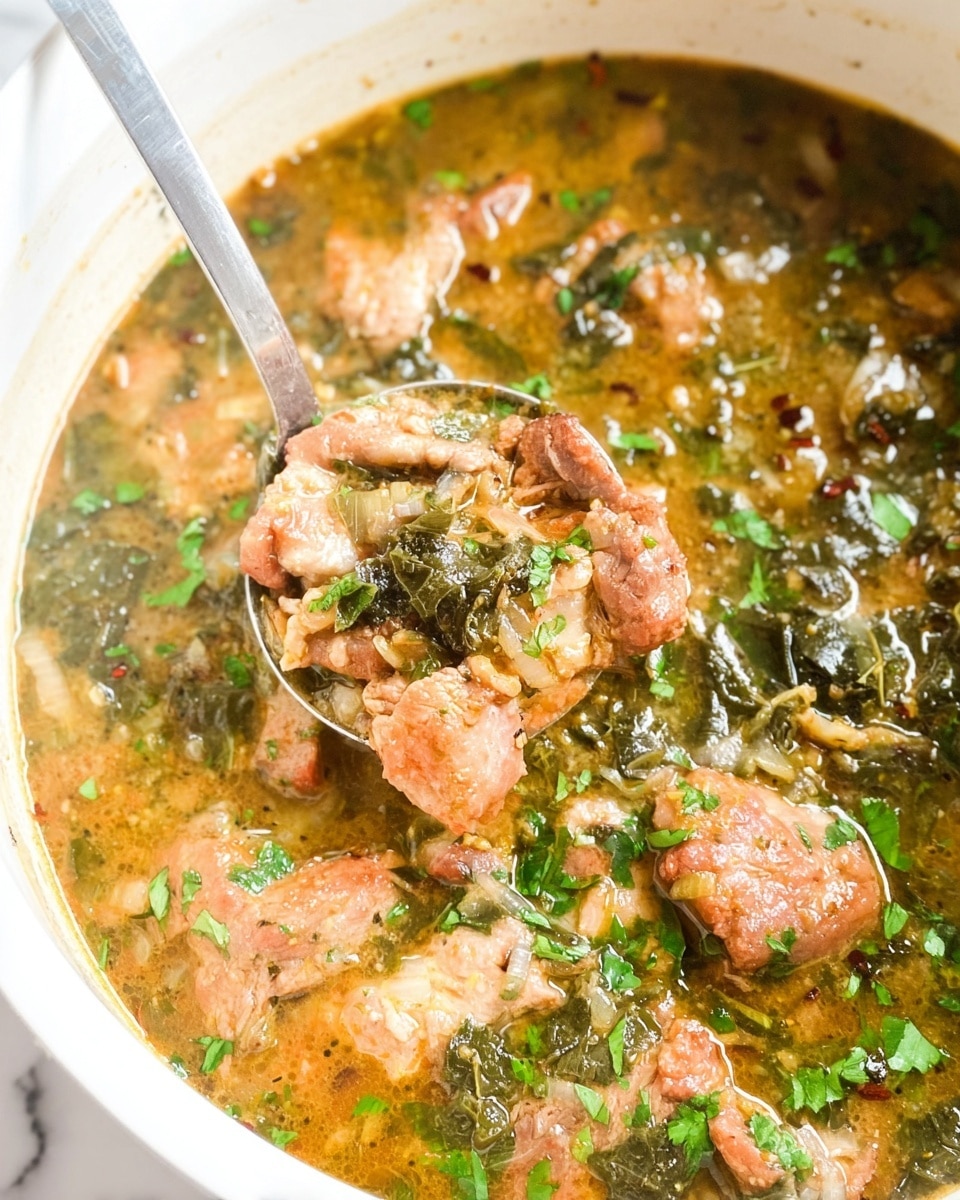 A close-up view of a thick stew inside a white pot, showing two layers: the base layer is a light brown, slightly chunky broth with small bits of herbs and spices floating through it, while the top layer consists of medium-sized chunks of cooked meat in a light brown color, mixed with dark green leafy vegetables and small pieces of translucent onion. A metal spoon is partially submerged in the stew, holding some meat and vegetables, with small green herb pieces sprinkled on top. The pot's interior shows some stew residue on the white sides. The photo is taken against a white marbled surface. Photo taken with an iphone --ar 4:5 --v 7