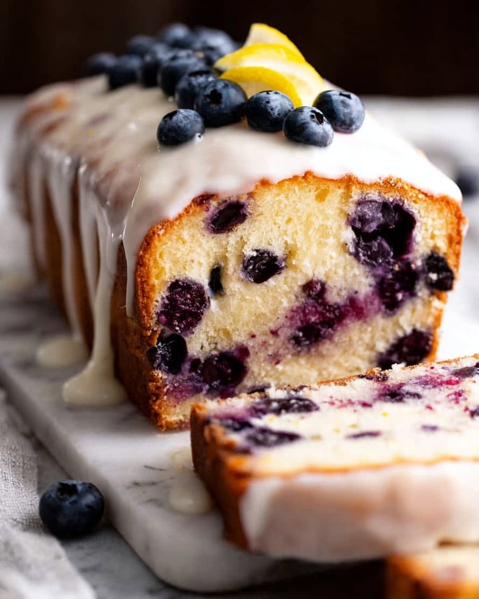 A thick loaf with a soft yellow inside filled with dark purple blueberries spread evenly through two dense layers, topped with a glossy white glaze that drips slightly down the sides, and decorated with fresh blueberries placed on top near a yellow candle. The loaf rests on light colored fabric on a white marbled surface with more blueberries scattered around. A woman's hand holds the back of the loaf, supporting it as a thick slice is cut and laid flat in front photo taken with an iphone --ar 4:5 --v 7