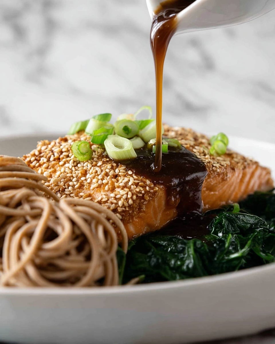 A sesame-crusted salmon fillet with a light brown outer layer full of sesame seeds sits on a bed of dark green cooked spinach leaves on a white plate. The inner part of the salmon is a lighter pinkish brown. Next to the salmon, there is a small pile of light brown soba noodles with a slight shine. A brown sauce is being poured over the salmon from above, with small green slices of scallion sprinkled on top of the sauce and salmon. The plate is set on a white marbled surface. photo taken with an iphone --ar 4:5 --v 7