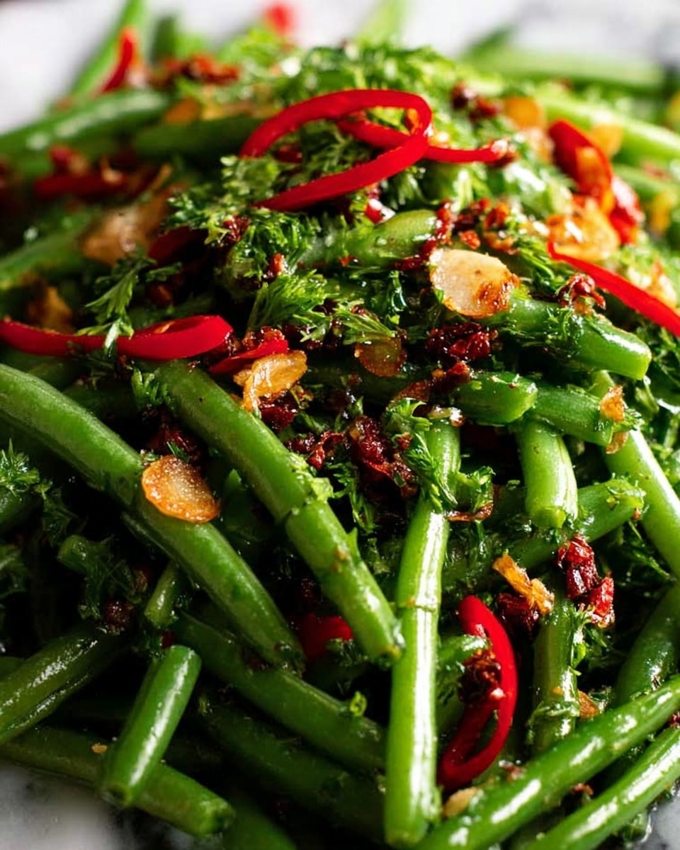 The image shows a close-up of a green bean salad with two main layers. The bottom layer is fresh, bright green beans that look crisp and slightly glossy, piled thickly. The top layer has thin red pepper strips, small green onion rings, chopped herbs, and crispy garlic slices scattered unevenly, adding splashes of red, light green, and golden brown colors. The mix looks fresh and vibrant with some dark toasted bits for contrast, all on a white marbled surface. Photo taken with an iphone --ar 4:5 --v 7