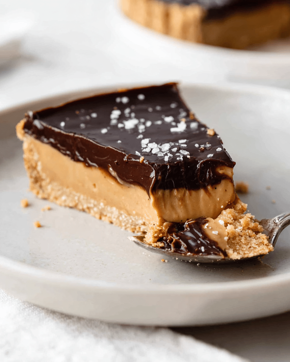 A slice of tart is shown on a white plate with a white marbled surface. The tart has three visible layers: the bottom layer is a crumbly golden-brown crust, the middle layer is a smooth, creamy light caramel color filling, and the top layer is a thick, shiny dark chocolate ganache sprinkled lightly with coarse salt crystals. A silver fork is lifting a bite of the tart, showing off the soft texture of the middle and top layers. There are some crumbs scattered on the plate. Photo taken with an iphone --ar 4:5 --v 7